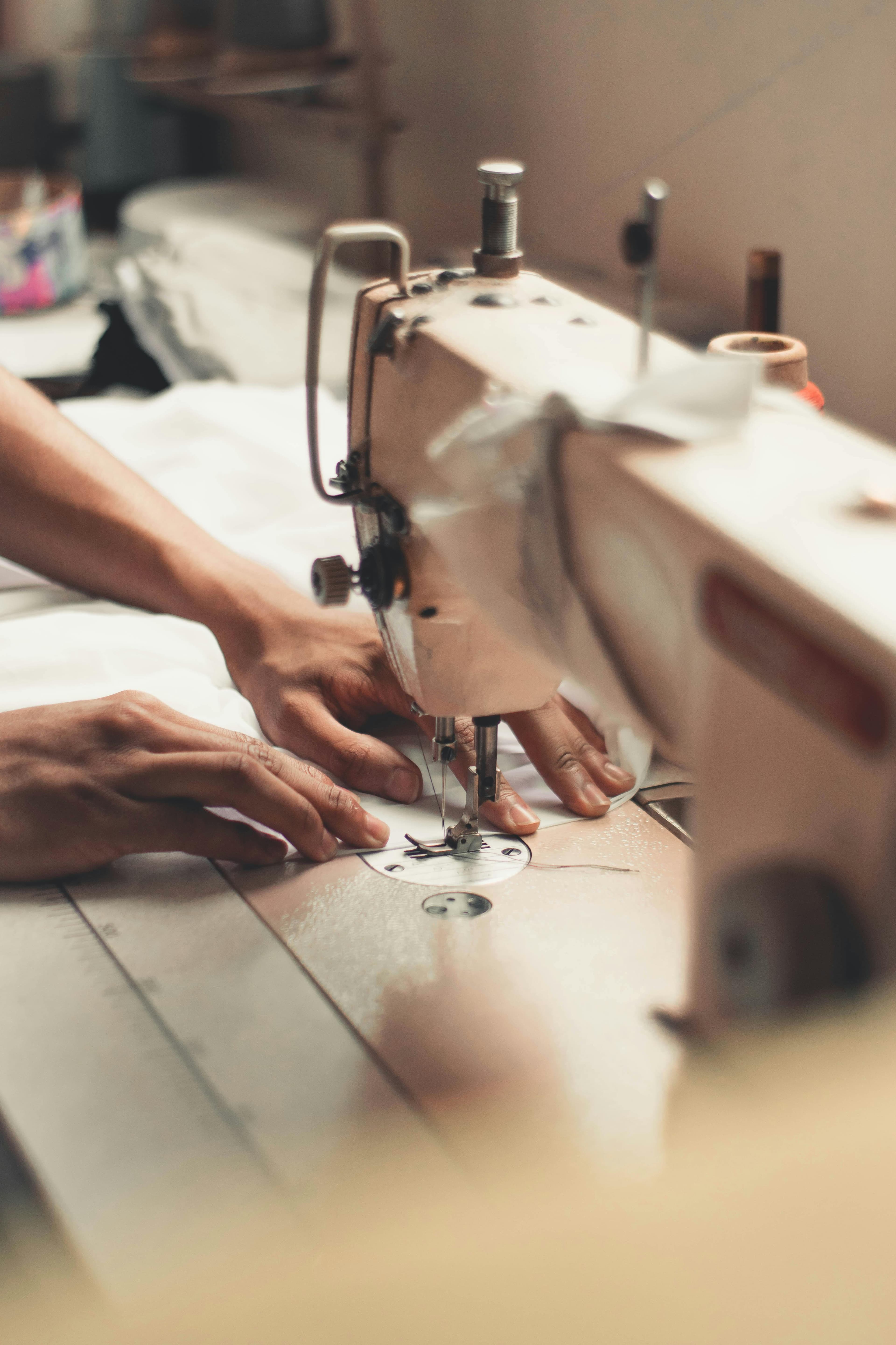 Hands stitching fabric on a sewing machine — Dominga garment craftsmanship in Sri Lanka